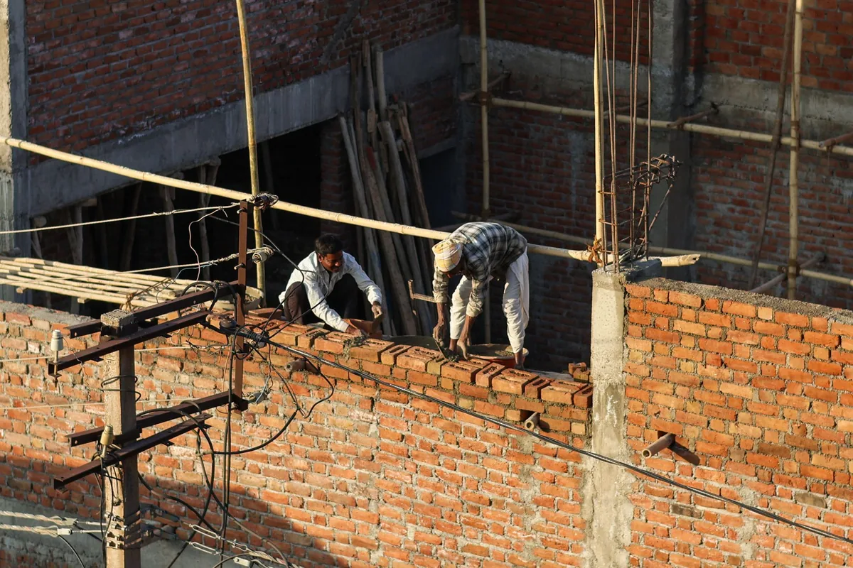 Albañiles reparando un muro de ladrillo en la zona común de una comunidad de vecinos